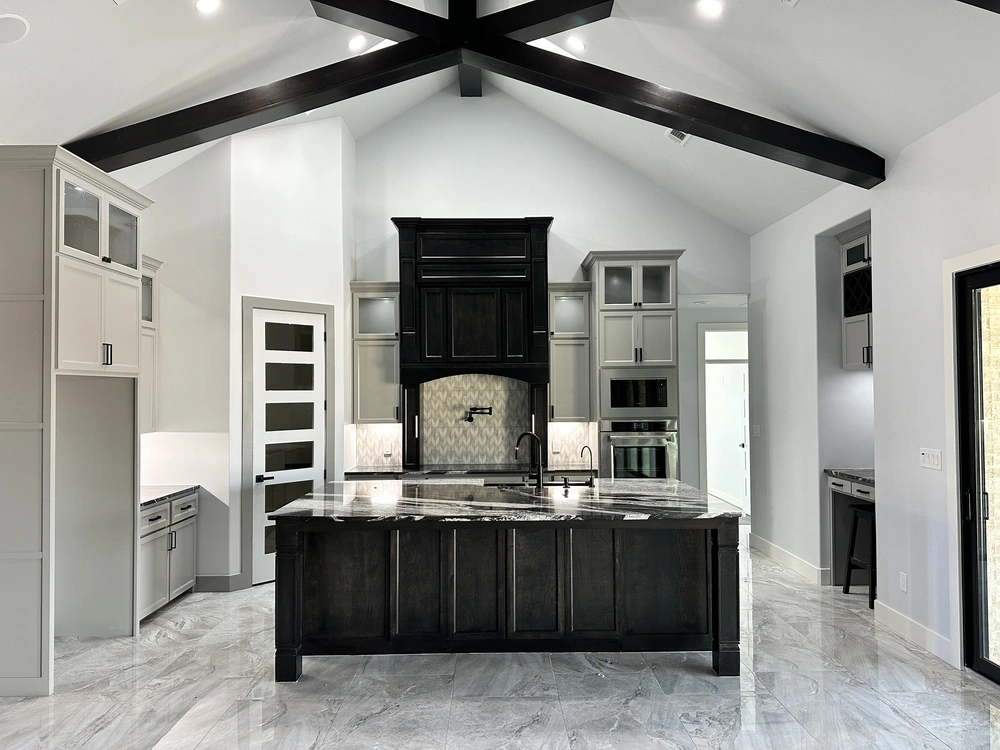 Full Home remodel with black and white kitchen grey cabinets, dark island, veined stone countertops and vaulted beam ceiling in Midland TX