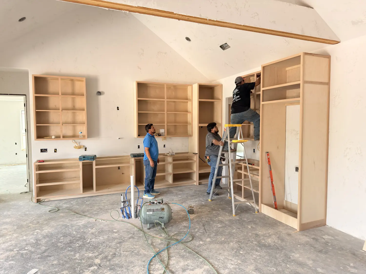 Crystal Cabinets craftsmen installing custom wood built-in shelving during a home build in Midland TX
