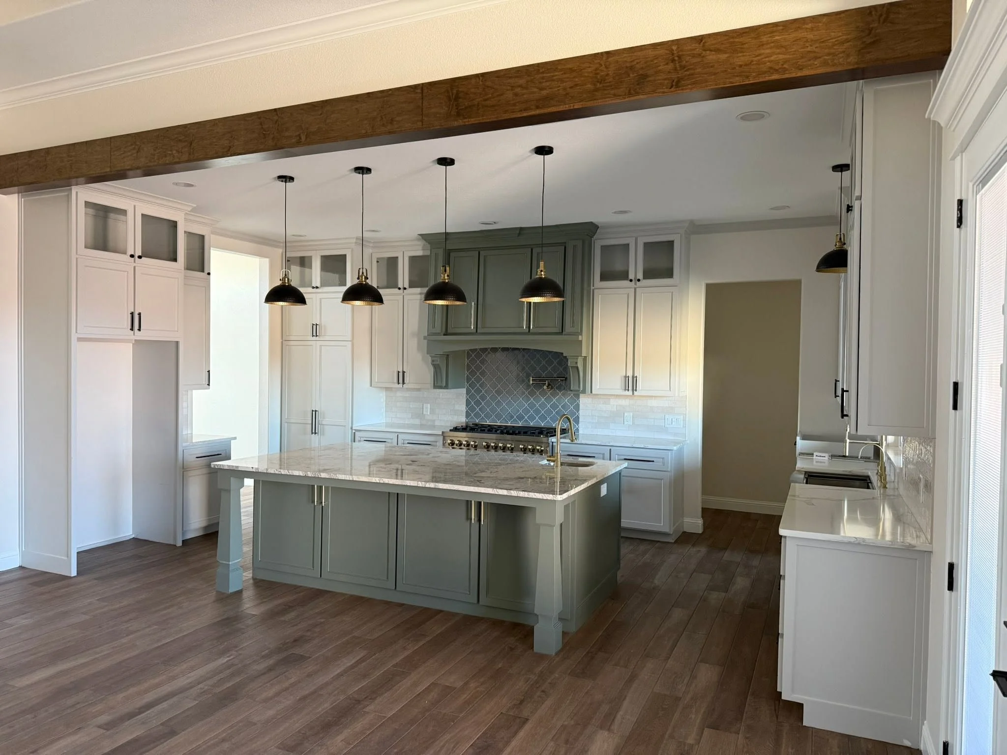 Custom kitchen remodel in Midland, TX featuring white shaker cabinets, a large quartz island, vaulted ceilings, premium lighting, and luxury finishes by Crystal Cabinets