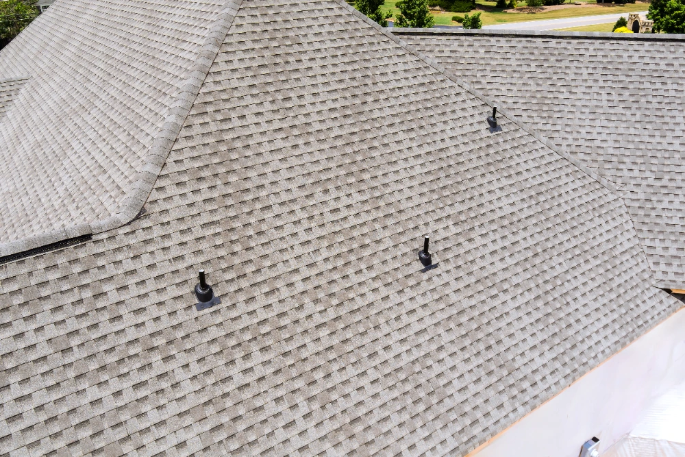Completed architectural asphalt shingle roof on a residential home with vent stacks in Midland TX