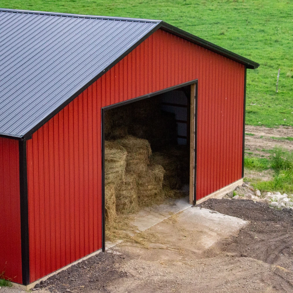 Red metal barn with black trim gable roof used for hay storage in Midland TX