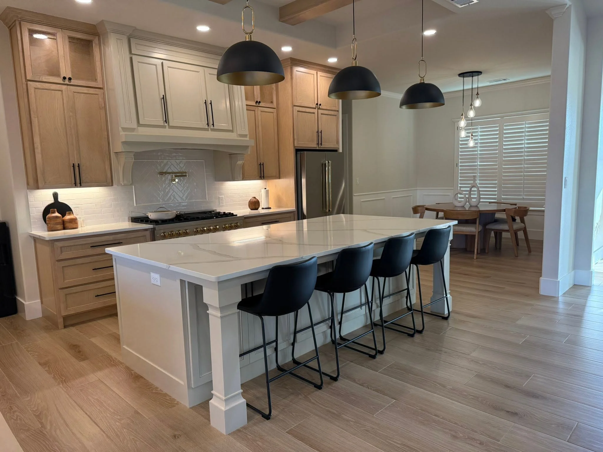 Two tone kitchen with natural wood cabinets, white island and stone waterfall countertop in a custom Midland TX home