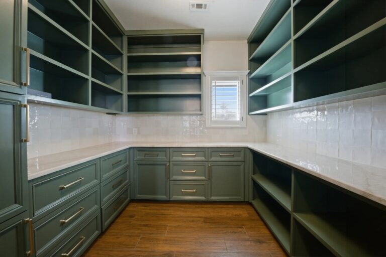 Custom cabinets with open shelving and white countertops in a sage green pantry, Midland TX