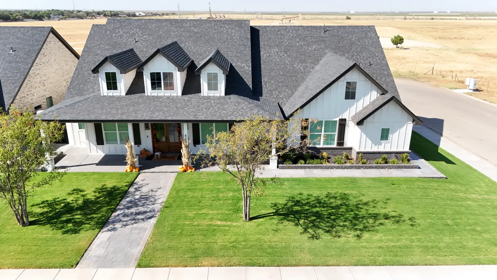 Mockingbird Heights: A board and batten farmhouse-style home with three dormers and a covered front porch.