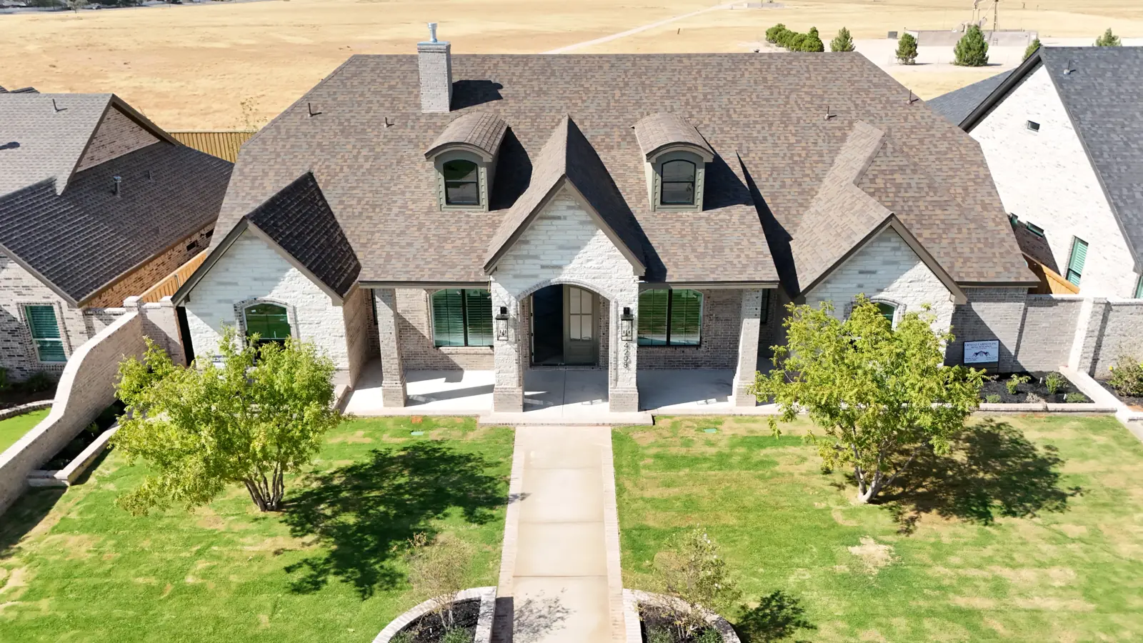 Mockingbird Heights: A white brick and stone home with arched dormers and a stone entry porch.