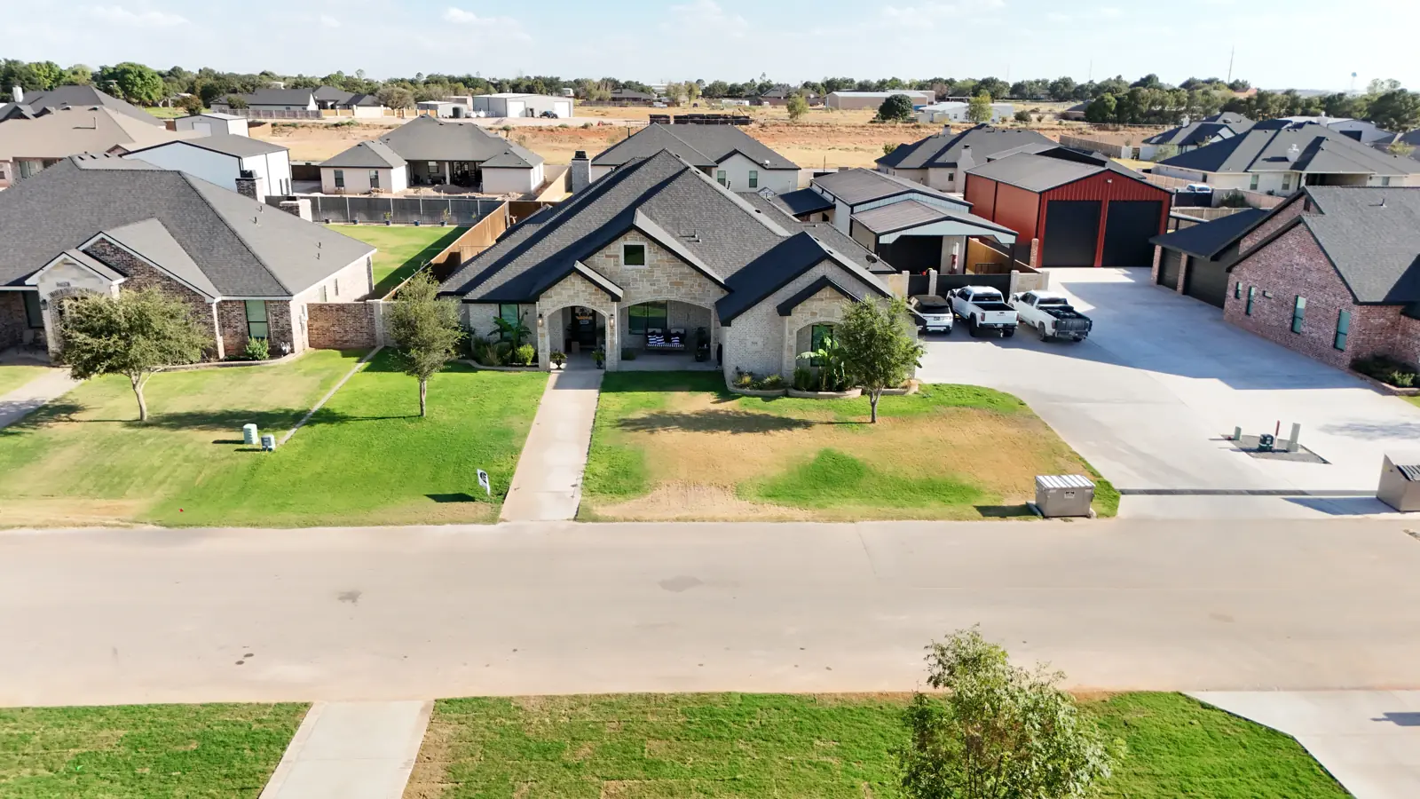 Saddleback Estates: A custom home with a red metal shop building beside the drive.